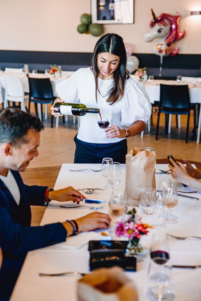 Serveuse schenkt wijn voor gasten aan tafel